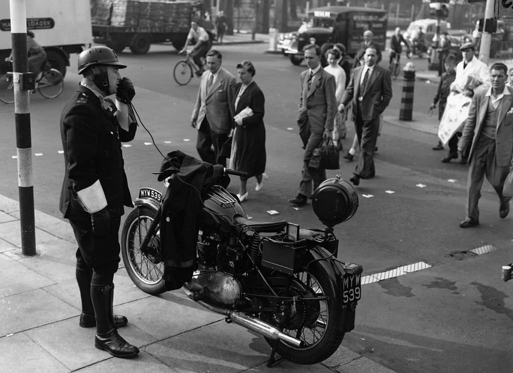 A police motorcyclist gives safety-first instructions to pedestrians at Kennington Oval, 1955