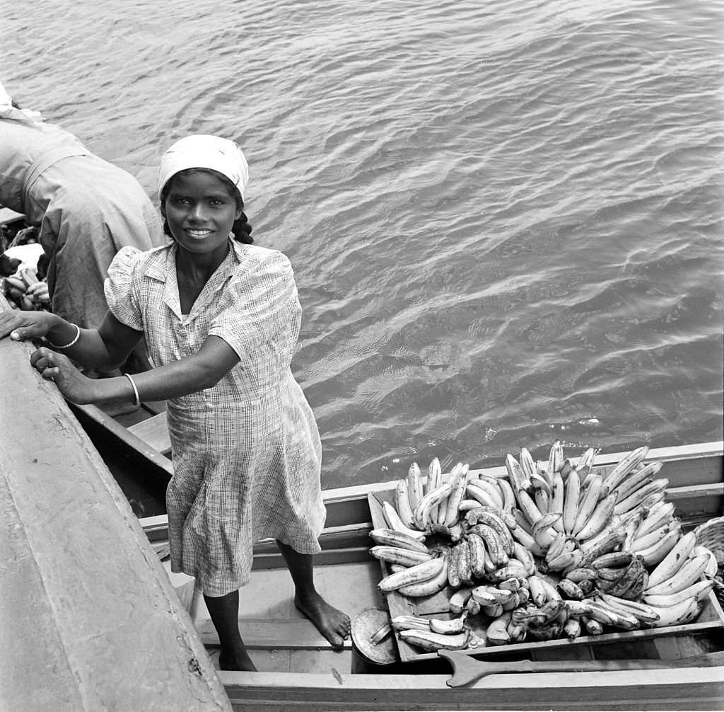 A local women loads bananas onto a boat in the harbor in Bridgetown, 1946