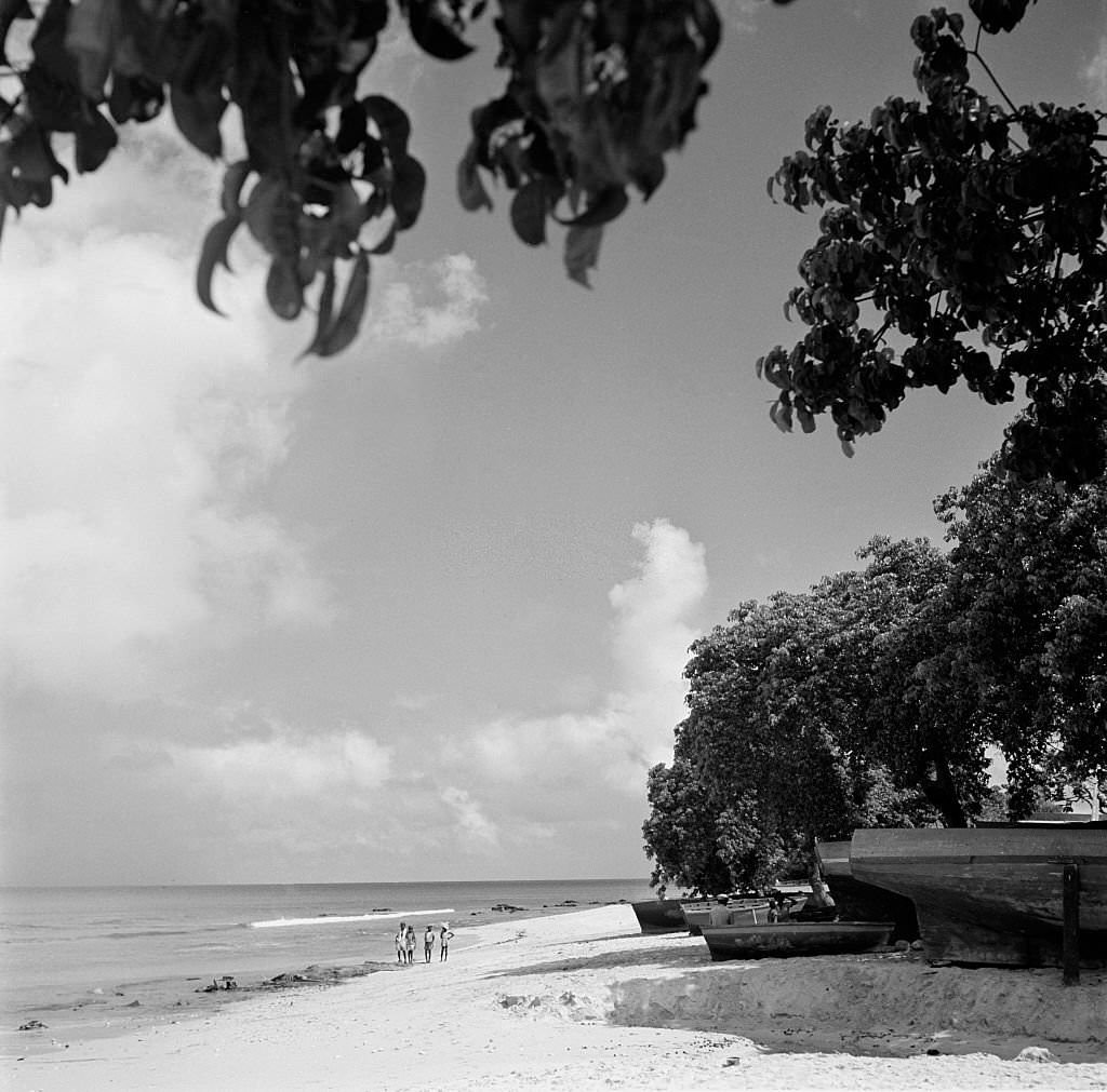 Locals walk on the sandy beach in Bridgetown, 1946