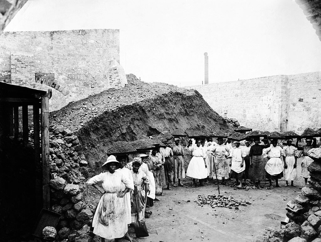 Women carrying coal in baskets on their heads to vessels in the port of Bridgetown, Barbados, 1910.
