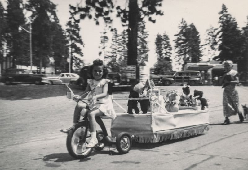 Little girl pulling a parade float with her tricycle, 1940s