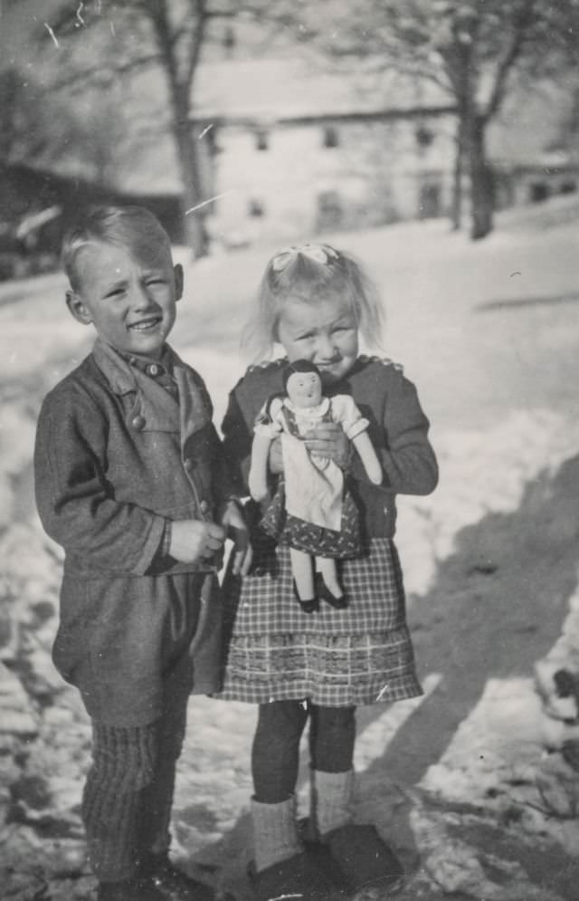 Children posing with a doll in the snow, 1944