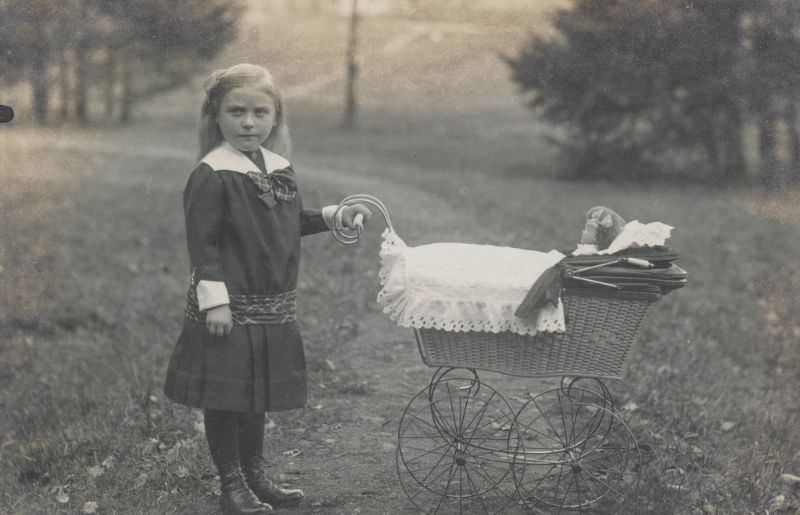Little girl pushing a stroller and doll, 1900s