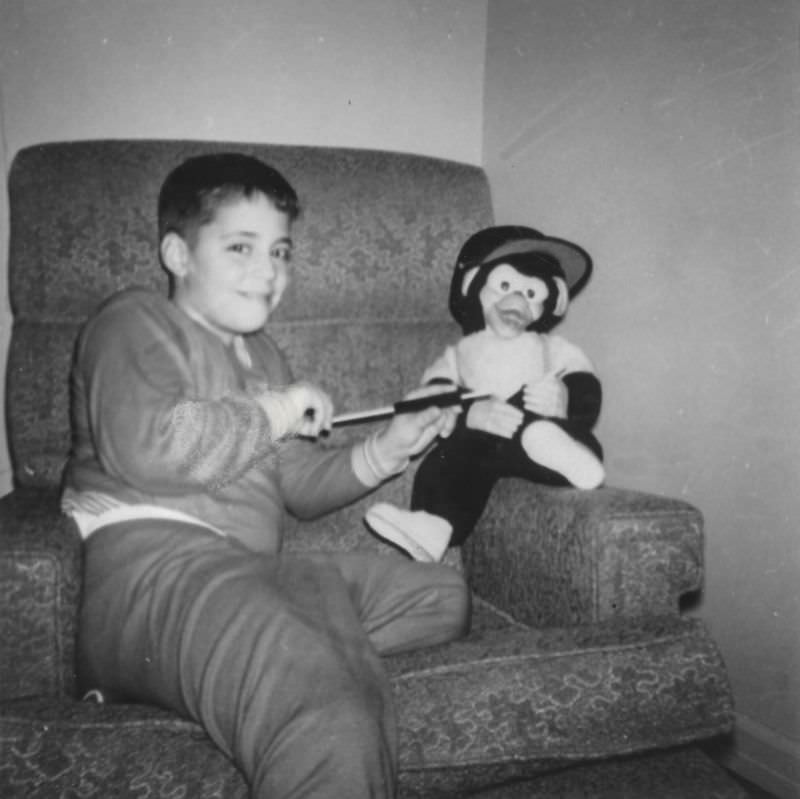 Little boy playing with a stuffed monkey, late 1950s