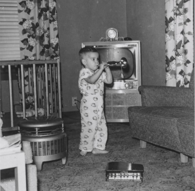 Little boy playing a toy trumpet, September 1956
