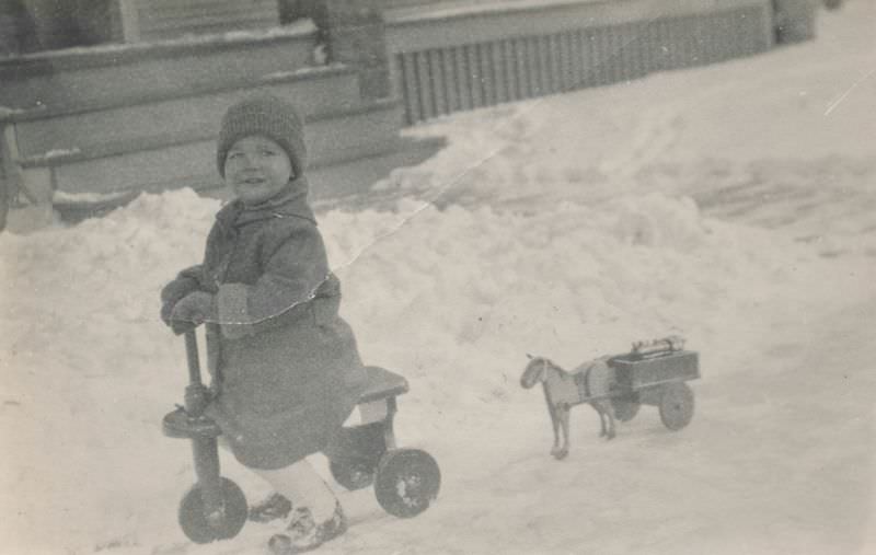 Child playing in the snow on a tricycle