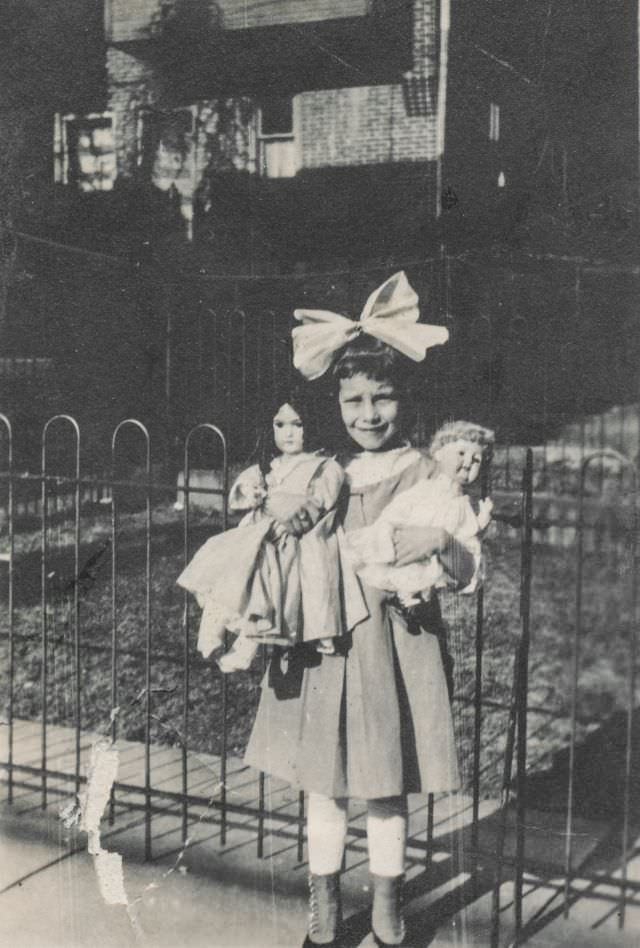 Little girl holding her dolls, 1910s