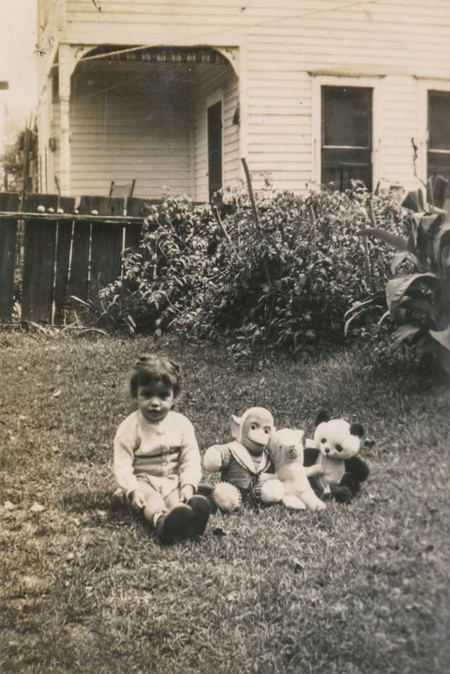 Child sits in the back yard with stuffed animals