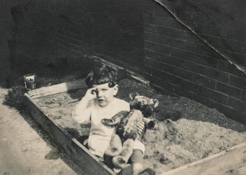 Crying boy with his teddy bear in a sandbox