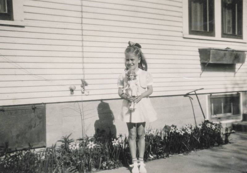 Little girl holding her doll outside