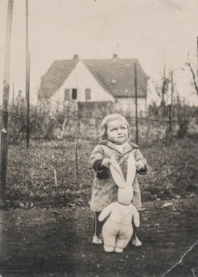 Little girl playing with a stuffed rabbit in the garden