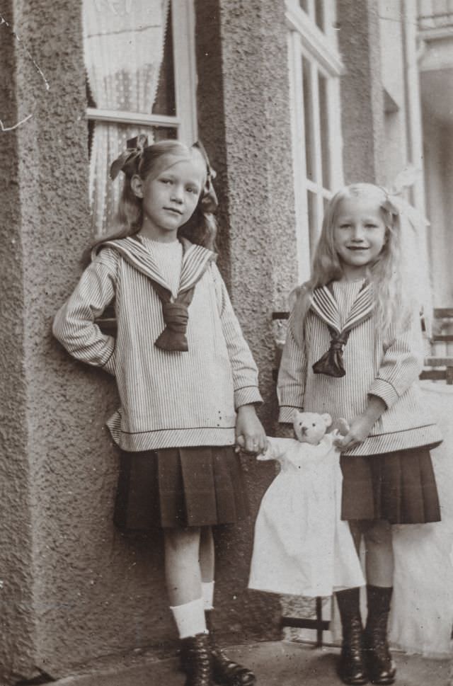 Two little girls standing outside with a stuffed bear, 1915