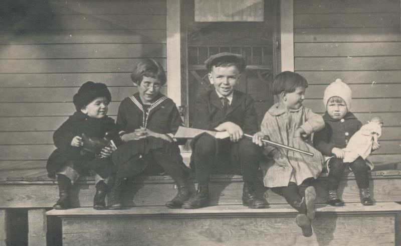 Children posing on a porch with their toys, 1920s
