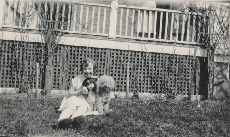 Little girl sitting outside with her doll and dog, 1920s