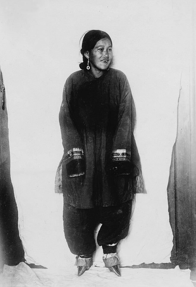 Chinese woman wearing holiday clothes and shoes for bound feet, 1910s