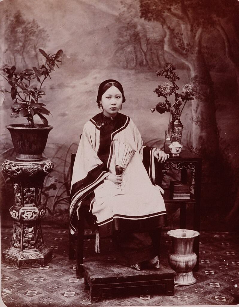 A portrait of young Chinese woman around the turn of the century whose tiny feet are the result of the Chinese tradition of foot-binding.
