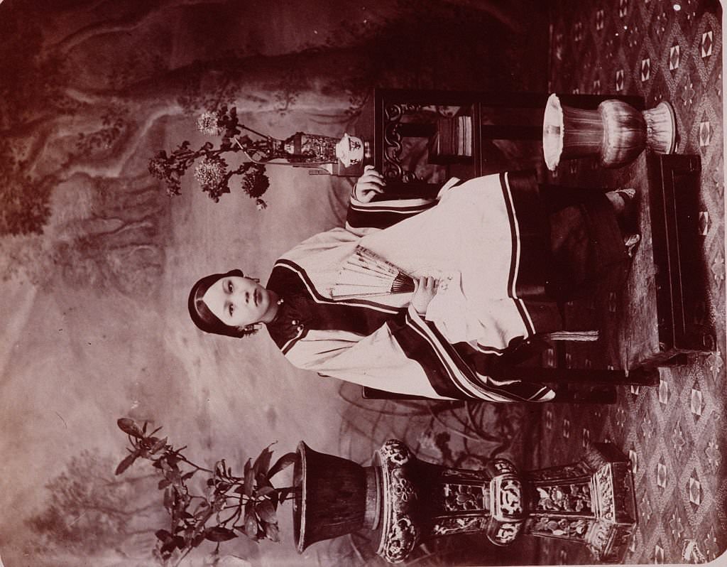 A portrait of young Chinese woman around the turn of the century whose tiny feet are the result of the Chinese tradition of foot-binding.