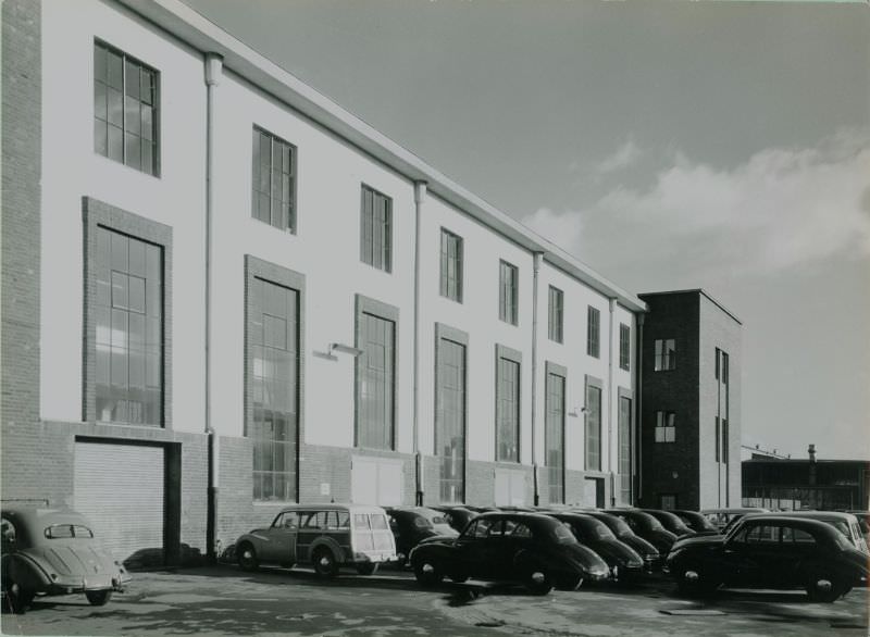 Side of factory building with sedans and estate conversions, 1951