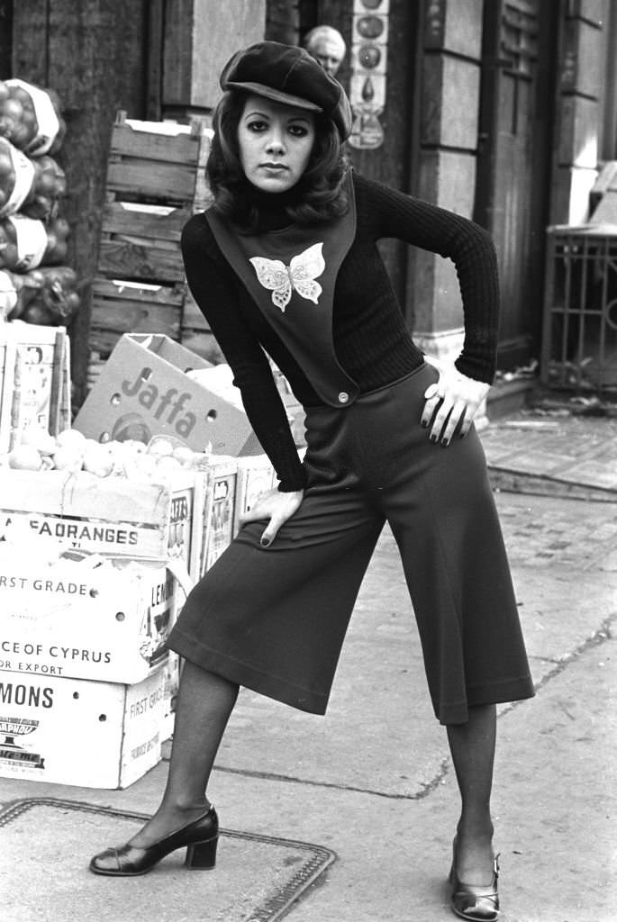 A young woman wearing culottes attached to a tabard-style top with a butterfly motif, in London's East End, 1970