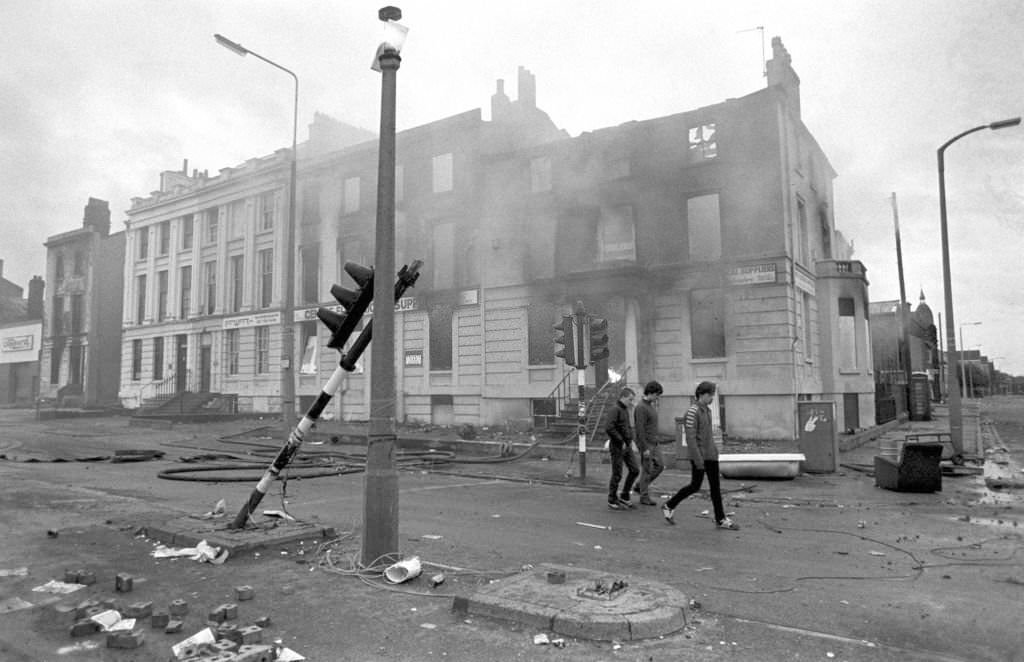 Teenagers survey the aftermath of a second night of violent rioting in the Toxteth district of Liverpool, 1981