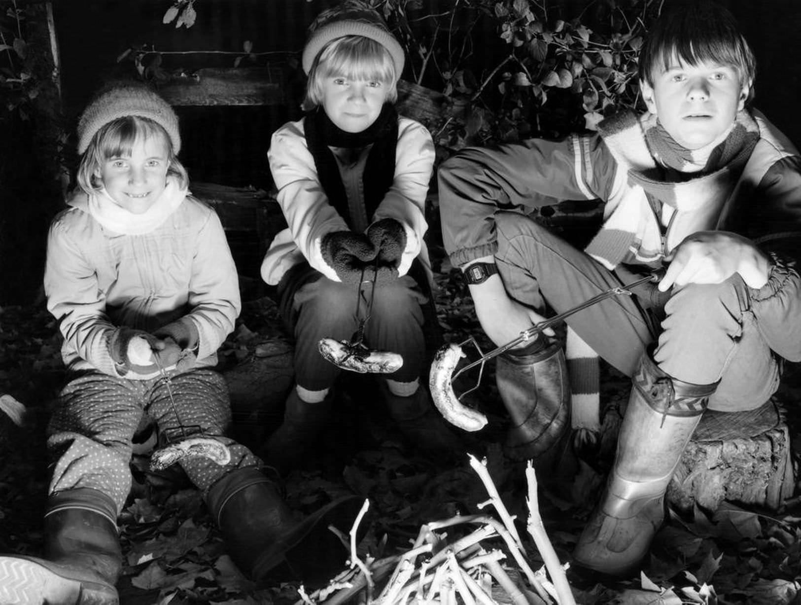 The original bonfire night banger. Children at a private Merseyside bonfire night part cooking sausages over the fire, 5th November 1985