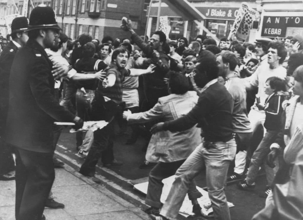 Stewards attempt to maintain a distance between the protestors and the police officers during an anti-police demonstration in the Toxteth area of Liverpool, 17th August 1981.