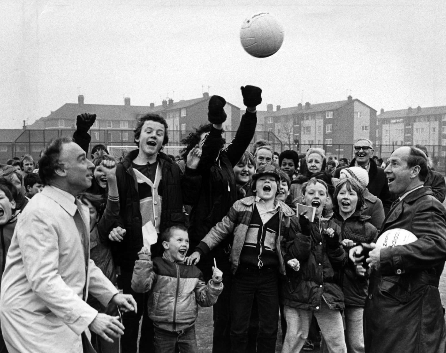 A head start for the new all-weather pitch as Sports Minister Neil MacFarlane (left) and Bobby Charlton give the youngsters in Toxteth something to cheer about. 24th February 1983