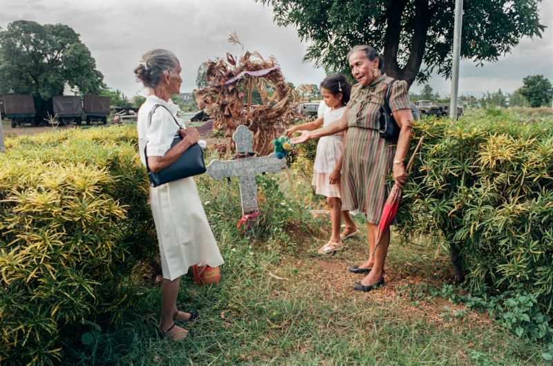 Doña Mercedes with her sister and her granddaughter Anna visit the grave of her son.