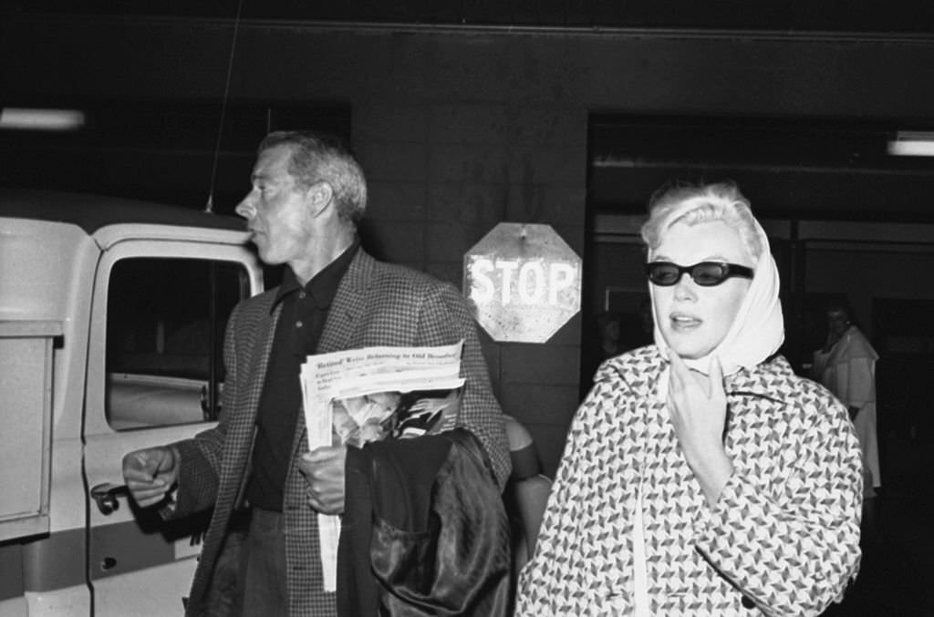 Marilyn Monroe and Joe DiMaggio trying to elude photographers and slip aboard plane to New York.