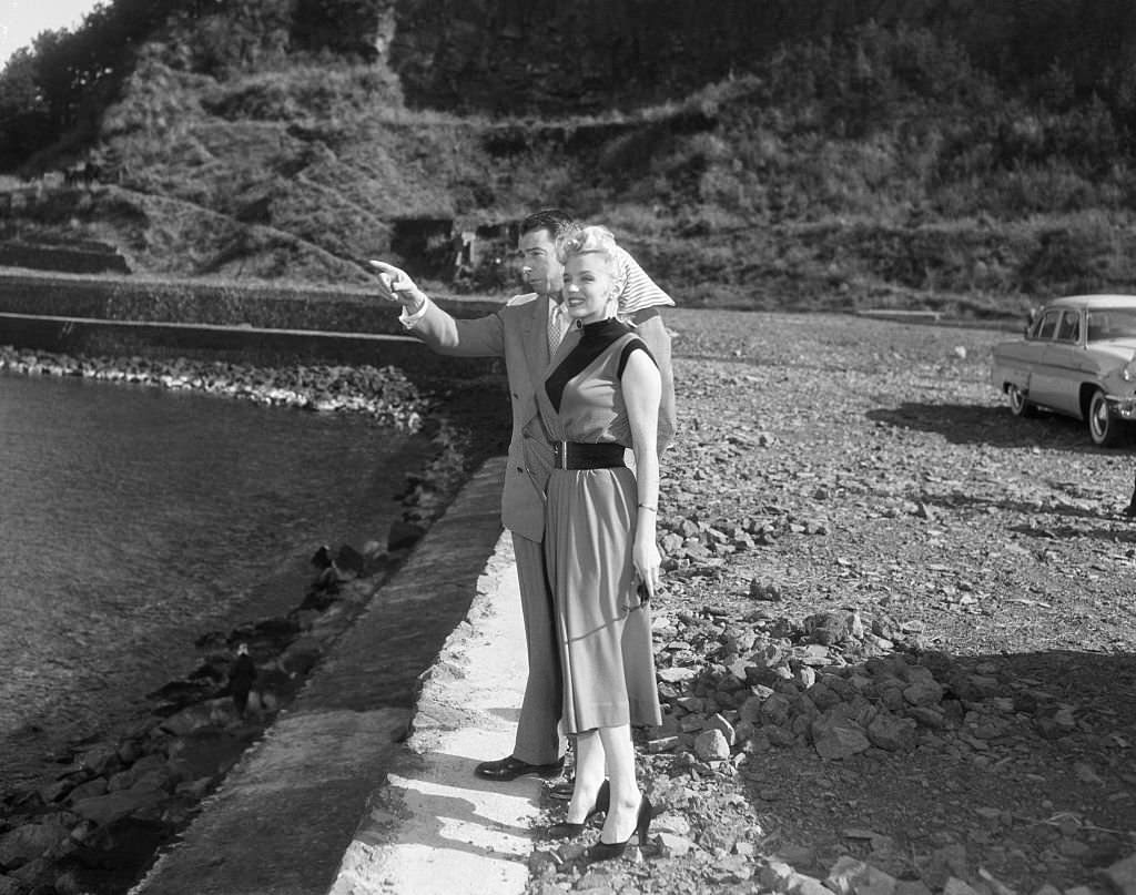 Joe DiMaggio and Marilyn Monroe visiting a little fishing village standing by a body of water.