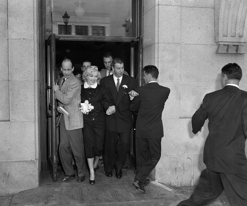 Marilyn Monroe and Joe Di Maggio press through a crowd of newsmen after their marriage in the office of Municipal Judge Charles Peery in San Francisco City Hall.