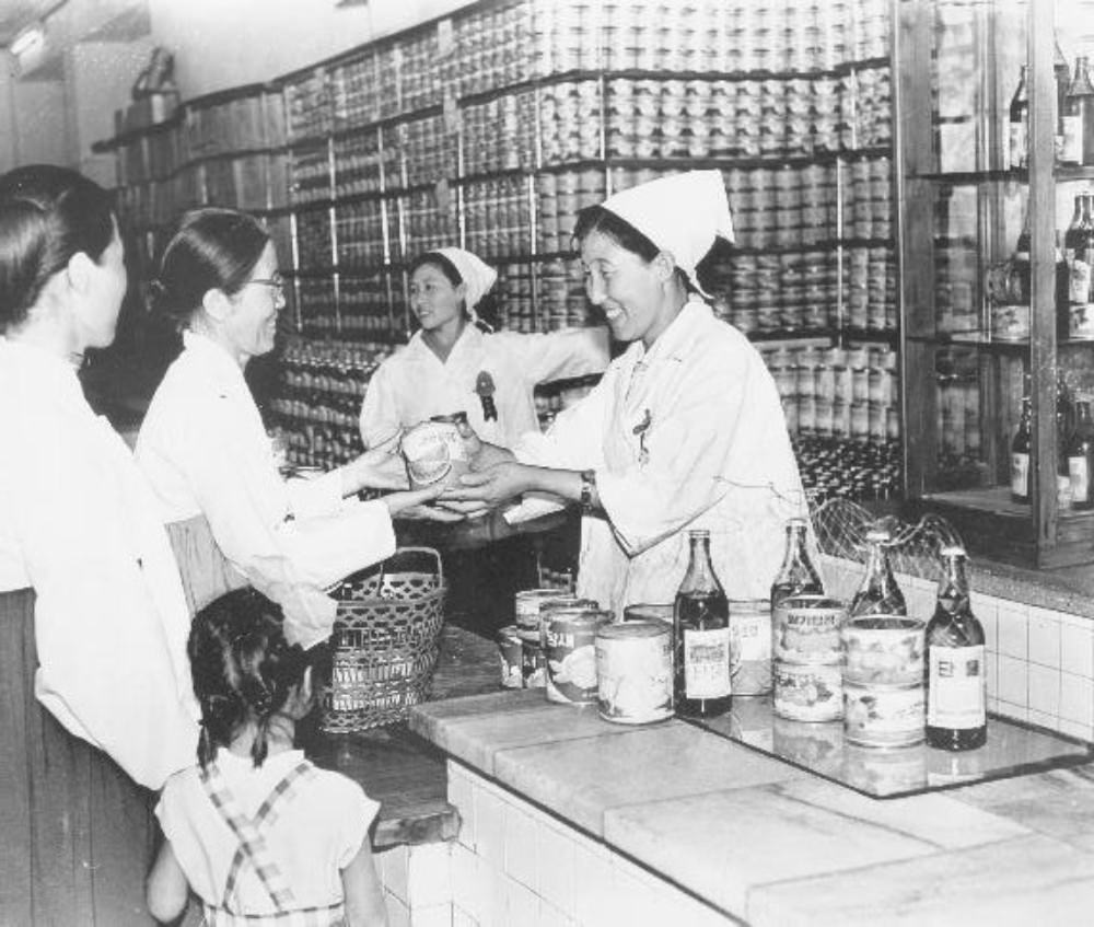 Clerks selling canned strawberry, watermelon, vegetables, bottles of juice, Pyongyang, North Korea, June 1972
