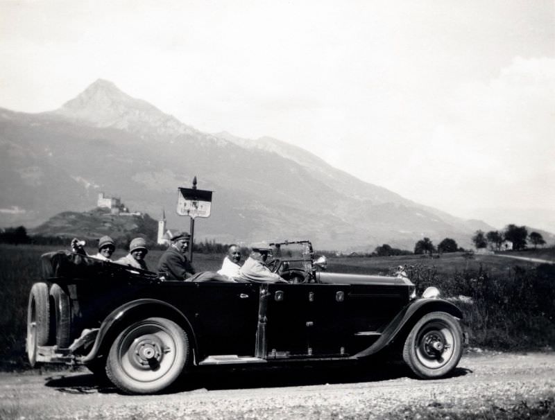 A company of five posing in a 1925 open-top Packard Eight Phaeton on a gravel road in the countryside, 1925