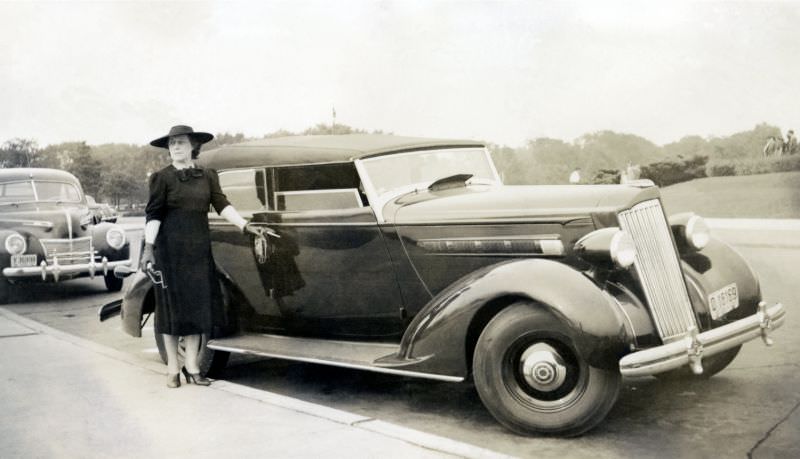 A well-to-do lady posing with a 1936 Packard 120 Convertible Sedan four-door convertible, 1939