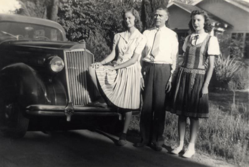 A father with two pretty teenage daughters posing in front of a 1936 Packard 120, 1940