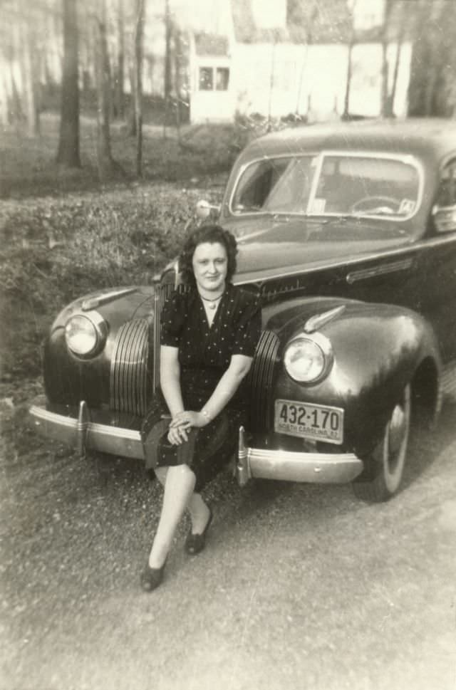 A lady in a polka dot dress posing on the bumper of a 1941 Packard Special.