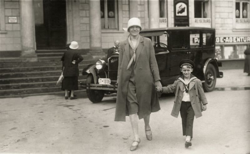 A woman and a little boy wearing a sailor suit on a city street.