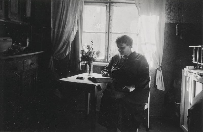 Elderly woman sitting in the dark reading a book, circa 1930s