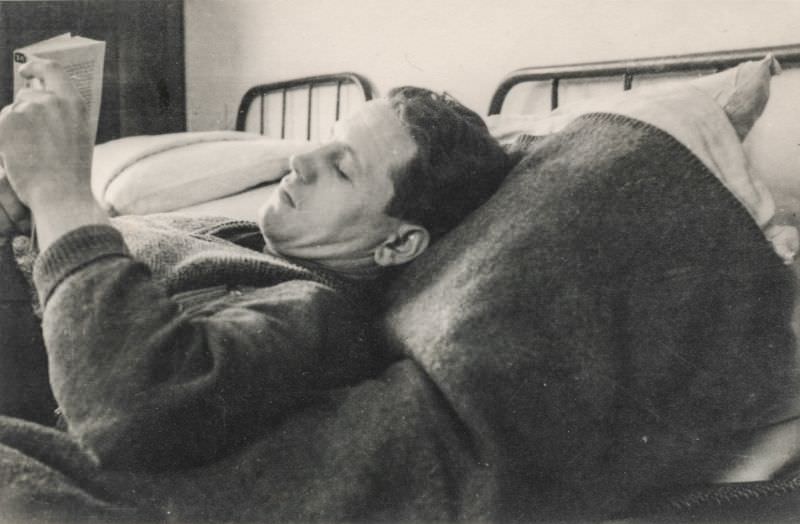 Man laying on a bed and reading a book