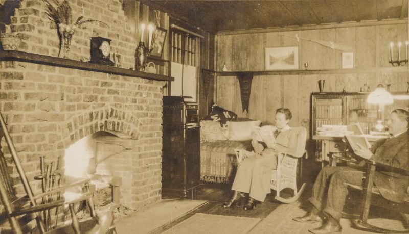 Couple reading books in front of a fireplace, circa 1910s
