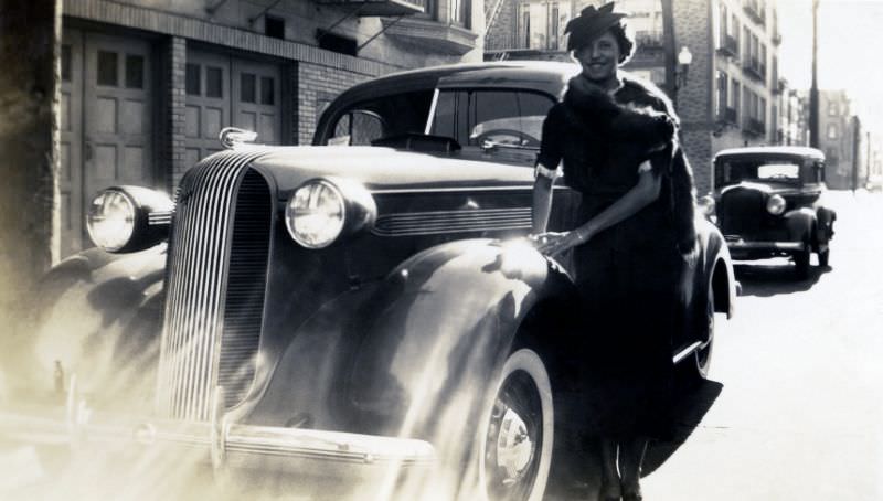 An elegant lady posing with a 1936 Pontiac in dramatic contre-jour lighting.