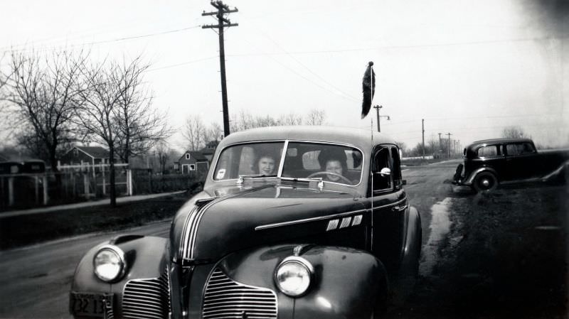 Two cheerful ladies posing inside a 1940 Pontiac on a country road under bleak winter skies.