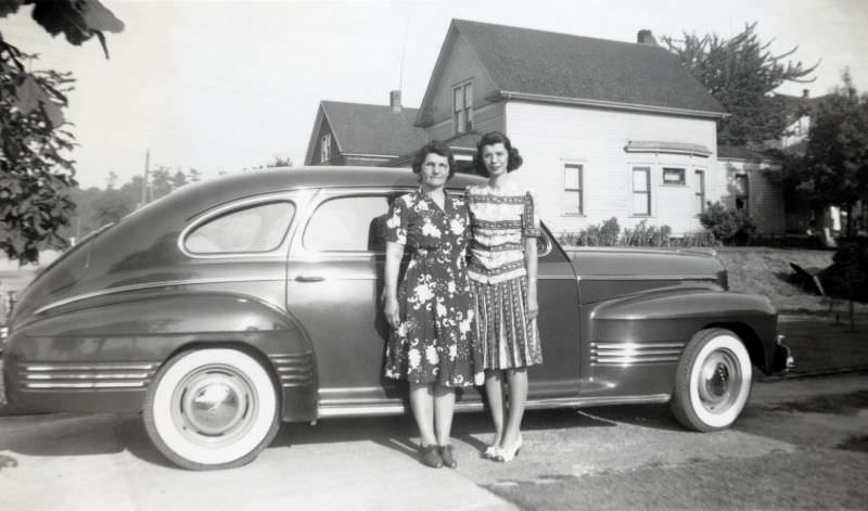 Two ladies, probably mother and daughter, posing with a 1941 Pontiac Streamliner Torpedo Eight in front of a middle class home, 1941