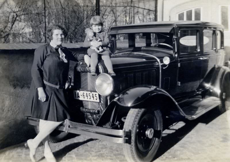 A young mother and her daughter posing with a 1929 Pontiac in winter sunshine.