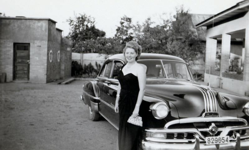 A stylish lady posing with a 1951 Pontiac in the backyard of a private home.
