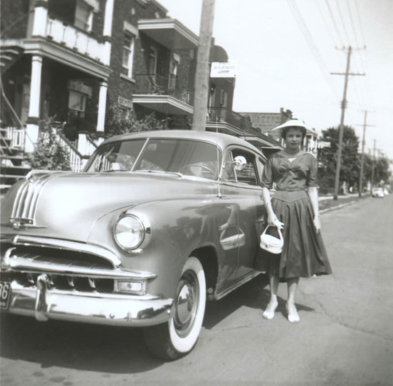 A young lady posing with a shiny Pontiac in a suburban street.