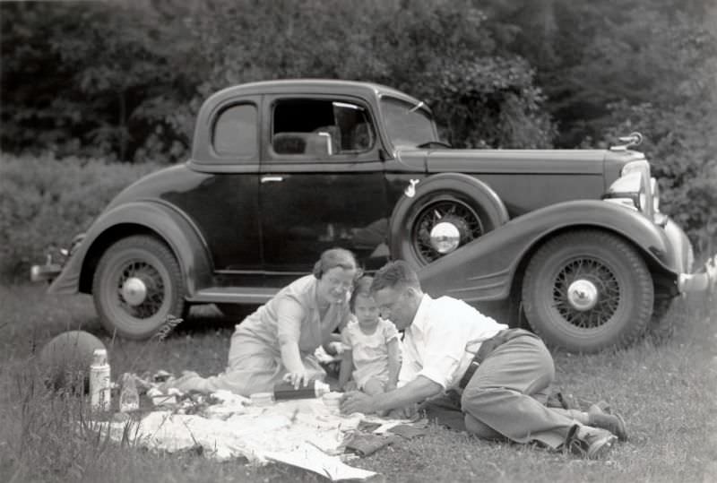 A family of three enjoying a picnic in the countryside.