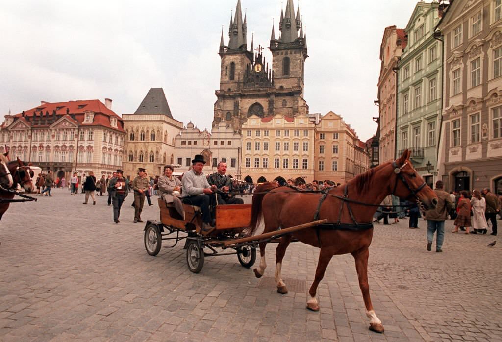 A horse and carriage rides through the Old Town Square in Prague.
