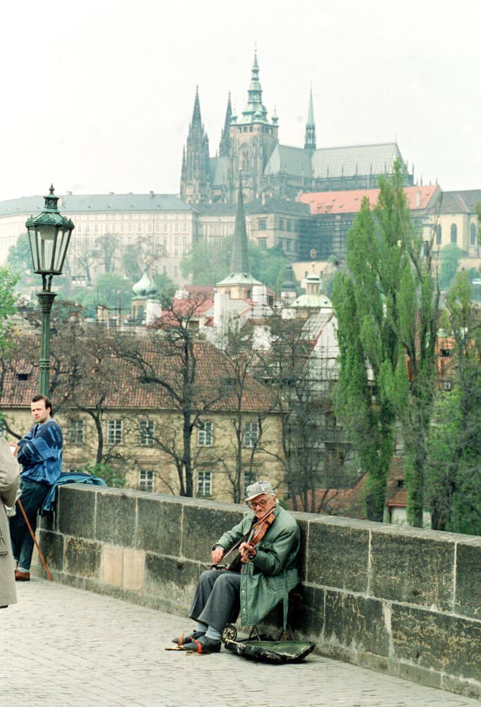 A musician plays on Charles Bridge in Prague in the shadow of the city's castle and St Vitus Cathedral.