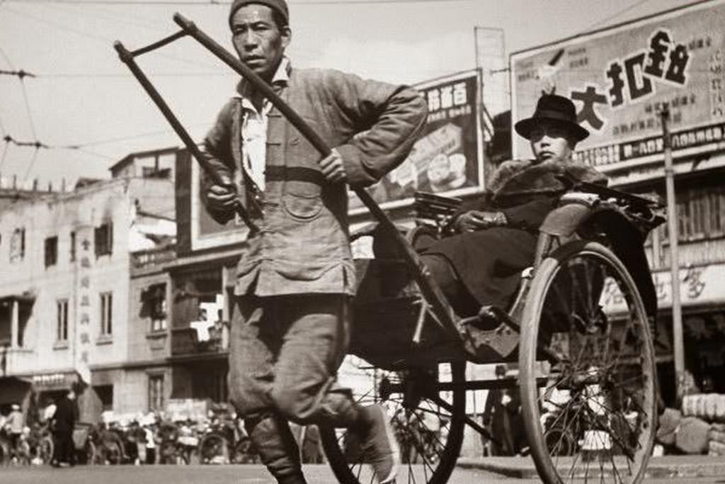 A rickshaw puller, with a lot of advertisements visible on the commercial street.